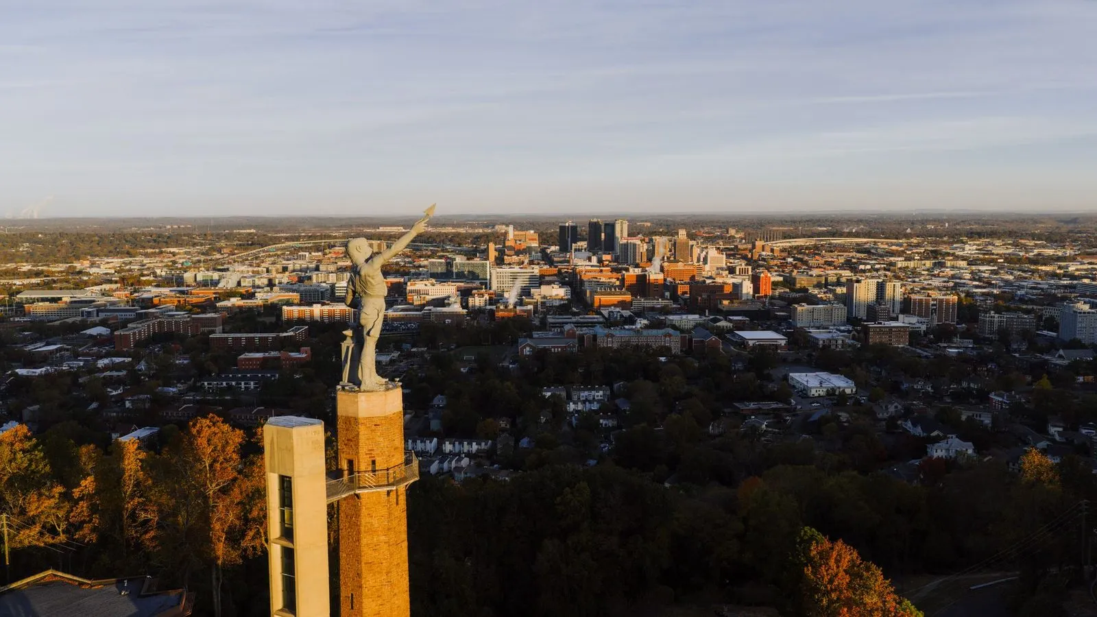 A large iron statue on a hilltop above Birmingham at sunset