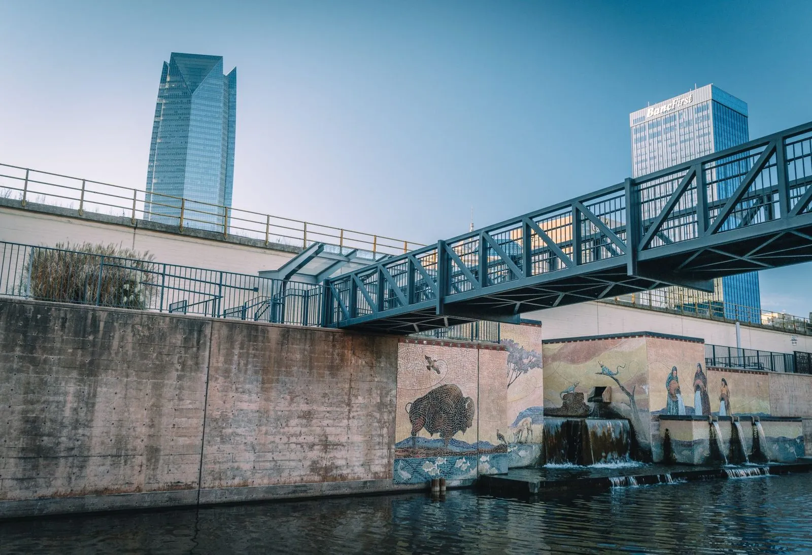 A footbridge over the Bricktown canal below downtown Oklahoma City towers