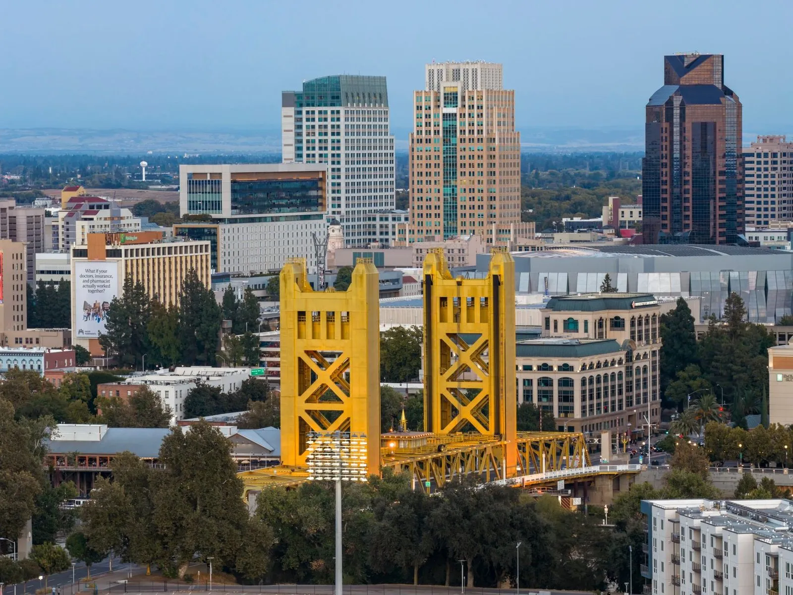 A golden lift bridge over the Sacramento River with the city behind it
