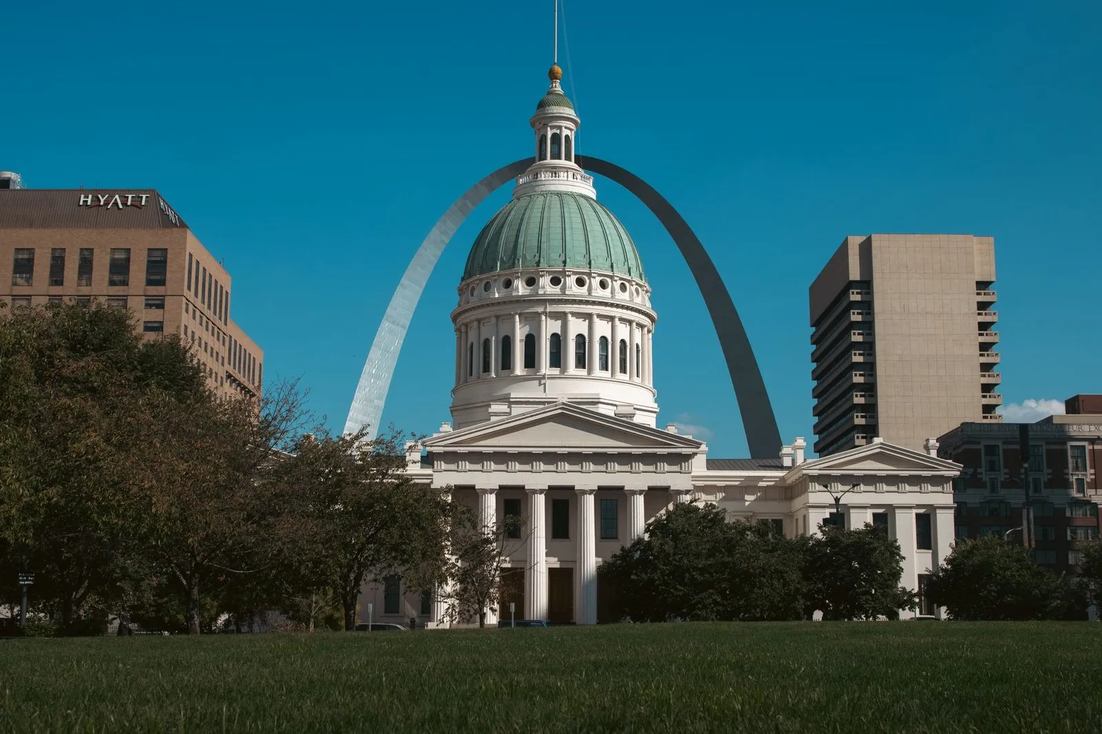 A domed courthouse in St. Louis with a tall steel arch rising behind it